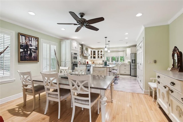 dining space with ceiling fan, plenty of natural light, ornamental molding, and light hardwood / wood-style flooring