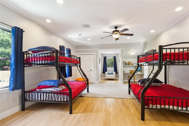 bedroom with ceiling fan, wood-type flooring, crown molding, and multiple windows