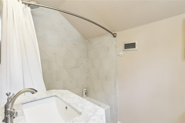 bathroom featuring sink, lofted ceiling, and a shower with curtain