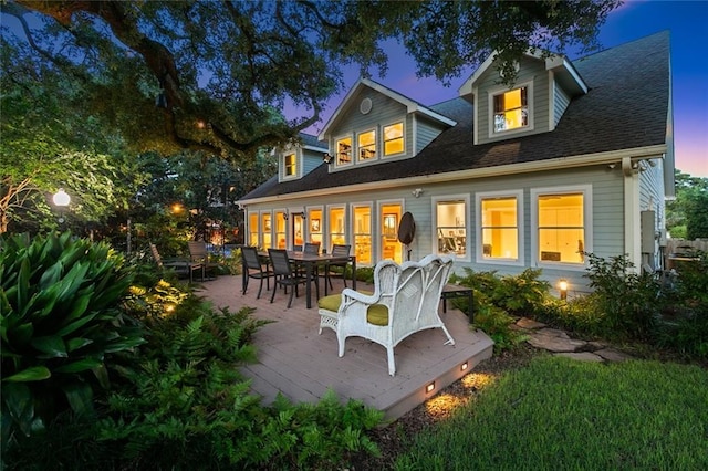 back house at dusk featuring a deck