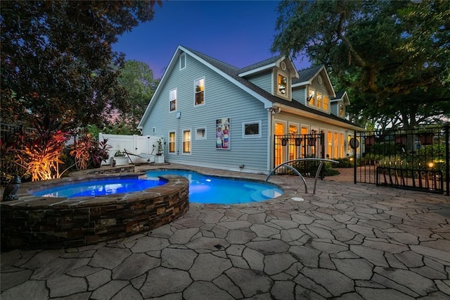 back of property featuring a patio area and a pool with hot tub