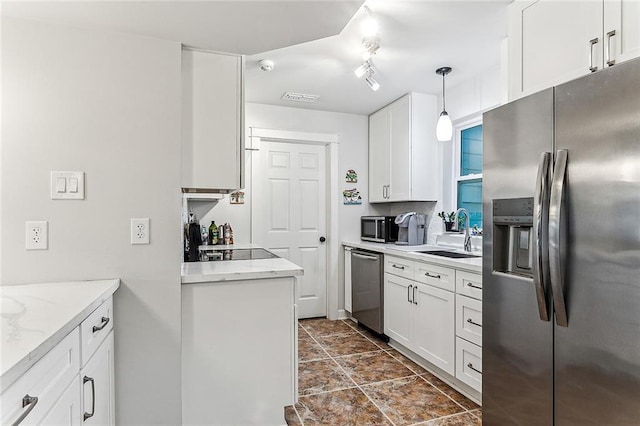 kitchen featuring stainless steel appliances, decorative light fixtures, white cabinets, light stone counters, and sink