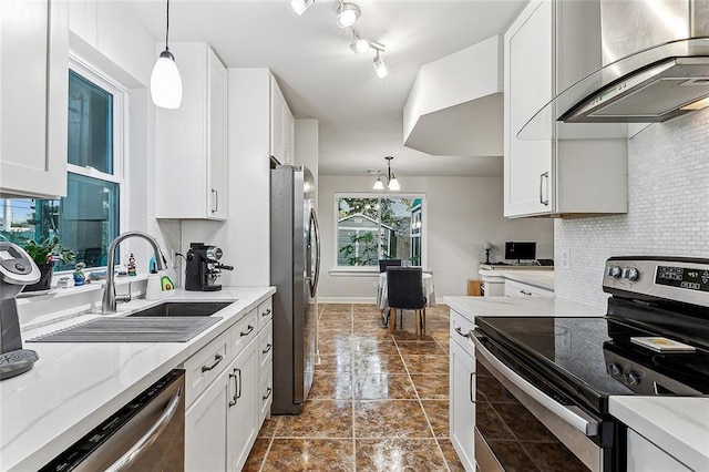 kitchen with pendant lighting, white cabinets, wall chimney range hood, stainless steel appliances, and an inviting chandelier