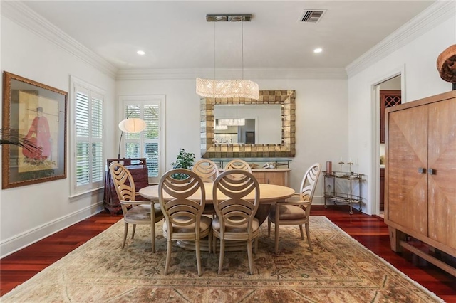 dining area featuring dark wood-type flooring, ornamental molding, and a notable chandelier