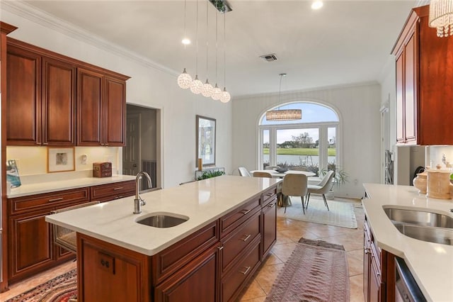 kitchen with sink, decorative light fixtures, stainless steel dishwasher, ornamental molding, and a kitchen island with sink