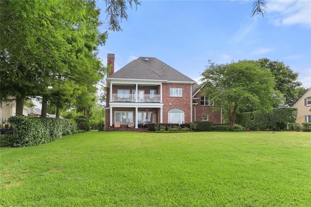 rear view of property featuring a balcony and a yard