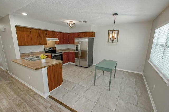 kitchen featuring stainless steel appliances, kitchen peninsula, pendant lighting, sink, and an inviting chandelier