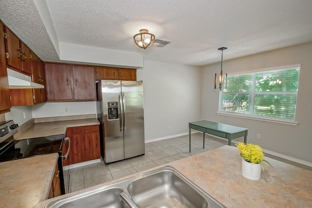 kitchen with sink, a textured ceiling, light tile patterned flooring, hanging light fixtures, and appliances with stainless steel finishes