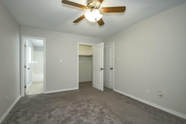 unfurnished bedroom with ensuite bath, dark colored carpet, ceiling fan, and a closet