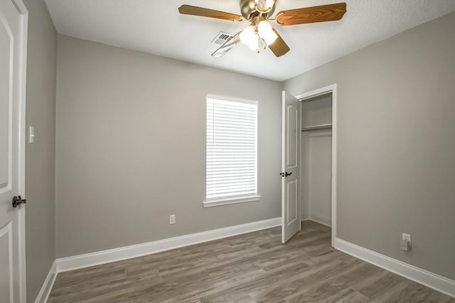 unfurnished bedroom with ceiling fan, a closet, and hardwood / wood-style flooring