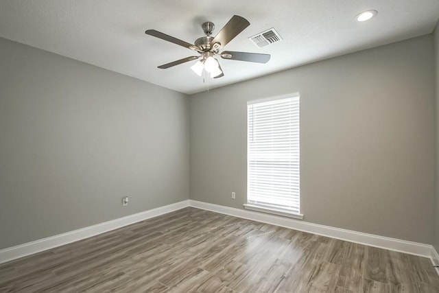 empty room with a healthy amount of sunlight, dark wood-type flooring, and ceiling fan