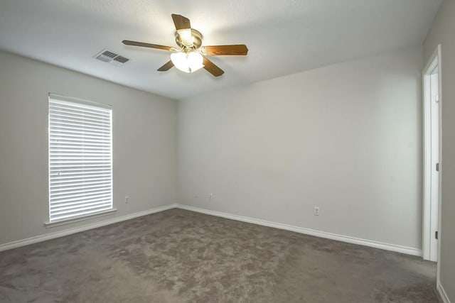 empty room featuring a healthy amount of sunlight, ceiling fan, and dark carpet