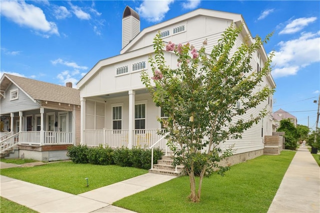 201 S Cortez St, New Orleans, LA 70119 - view of front of property with covered porch, a front yard, and a chimney