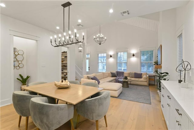 dining room featuring light hardwood / wood-style flooring, vaulted ceiling, and a chandelier