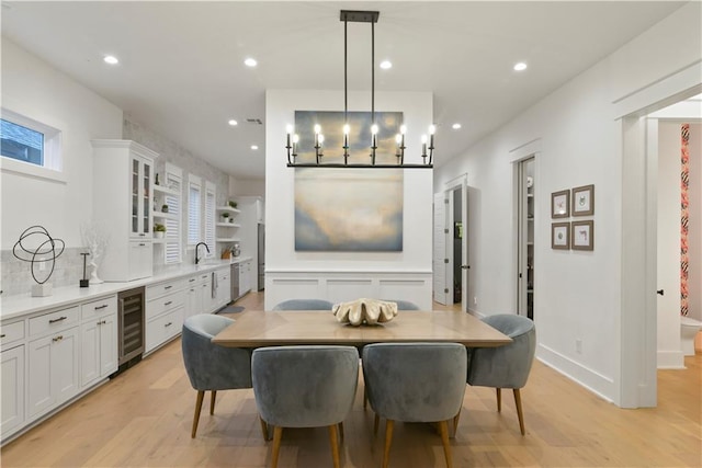 dining area with light wood-type flooring, wine cooler, and sink