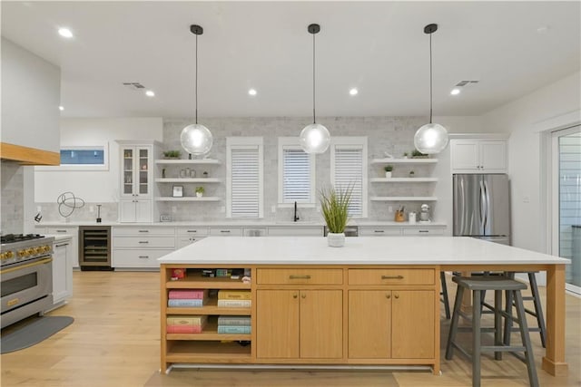 kitchen with white cabinets, stainless steel appliances, a kitchen island, and wine cooler