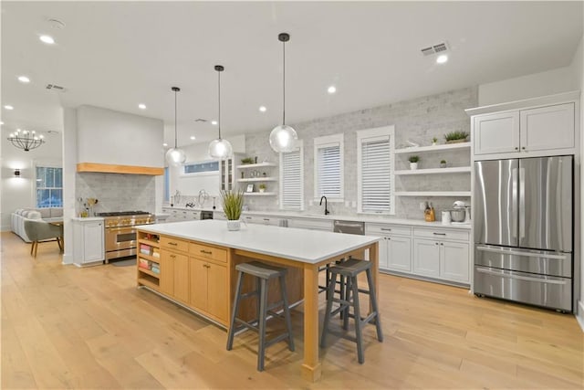 kitchen with stainless steel appliances, a center island, a kitchen bar, decorative backsplash, and white cabinetry