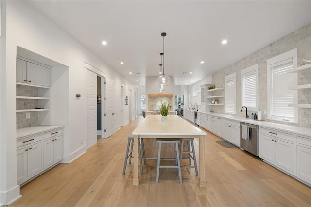 201 S Cortez St, New Orleans, LA 70119 - kitchen featuring open shelves, stainless steel dishwasher, light wood-type flooring, a breakfast bar, and a kitchen island