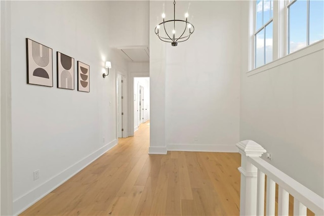 hallway with an inviting chandelier and light hardwood / wood-style flooring