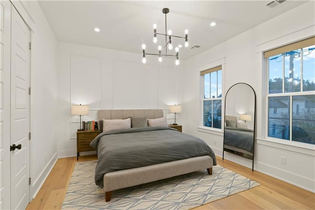 bedroom with light wood-type flooring and a chandelier