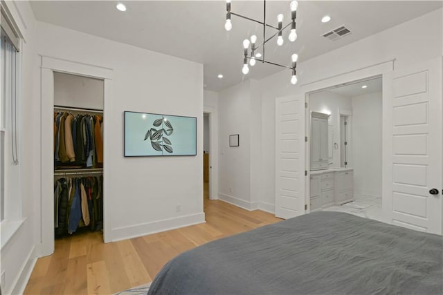 bedroom with a closet, an inviting chandelier, a spacious closet, light hardwood / wood-style flooring, and ensuite bathroom