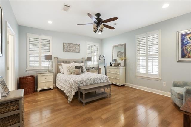 bedroom with ceiling fan, multiple windows, and hardwood / wood-style flooring