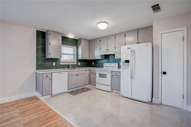 kitchen featuring sink, white appliances, backsplash, and gray cabinets