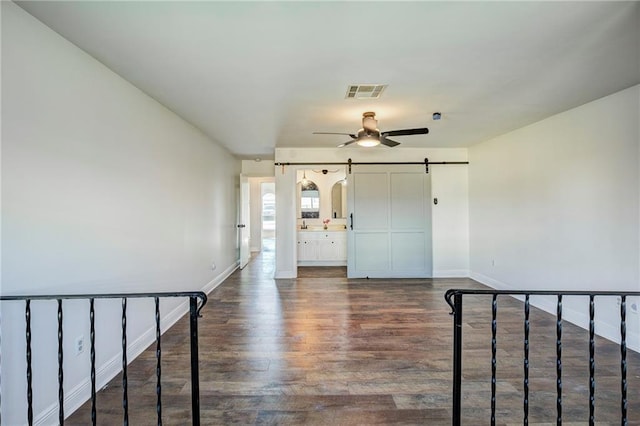 interior space featuring dark hardwood / wood-style flooring, ceiling fan, and a barn door