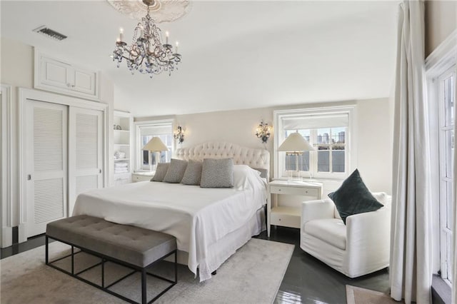 bedroom featuring light hardwood / wood-style flooring, an inviting chandelier, and a closet