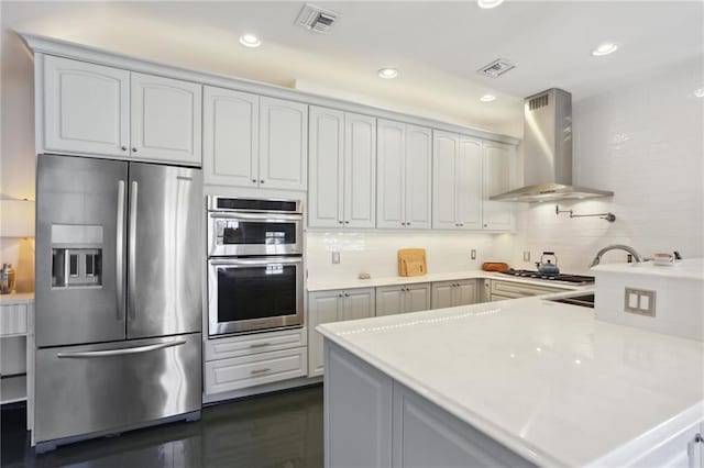 kitchen with white cabinets, appliances with stainless steel finishes, and wall chimney exhaust hood