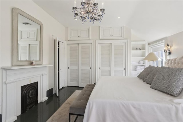 bedroom featuring dark wood-type flooring, two closets, and a notable chandelier