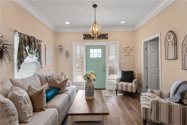 living room with wood-type flooring, a chandelier, and crown molding