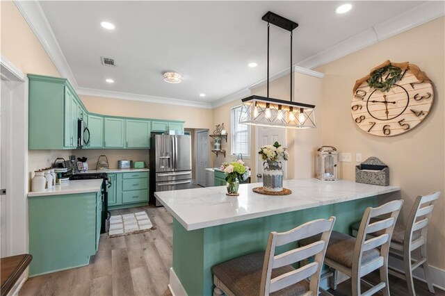 kitchen with appliances with stainless steel finishes, hanging light fixtures, kitchen peninsula, ornamental molding, and light hardwood / wood-style flooring