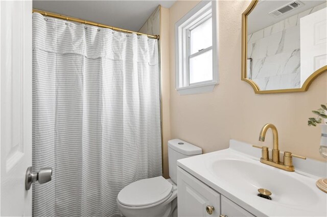 bathroom featuring toilet, vanity, and walk in shower