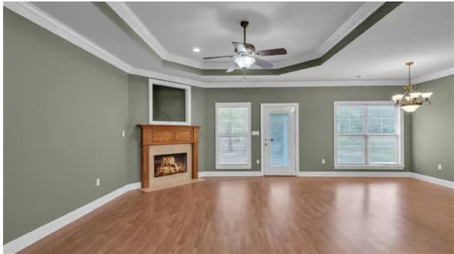 unfurnished living room with ornamental molding, light hardwood / wood-style flooring, ceiling fan with notable chandelier, and a tray ceiling