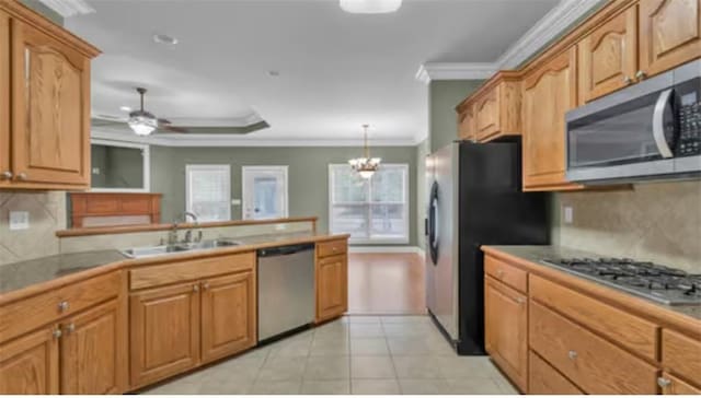 kitchen with sink, ceiling fan with notable chandelier, pendant lighting, crown molding, and appliances with stainless steel finishes