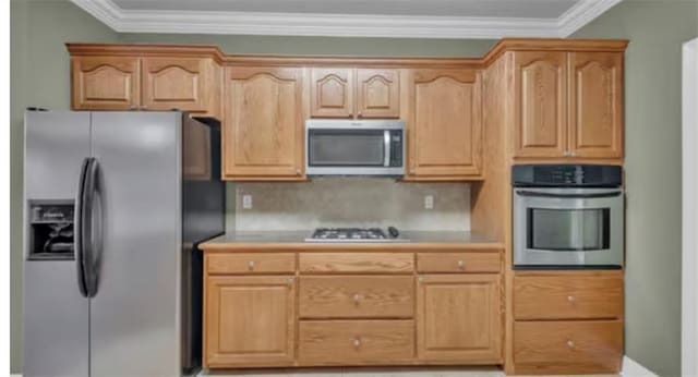 kitchen with appliances with stainless steel finishes, crown molding, light brown cabinets, and decorative backsplash