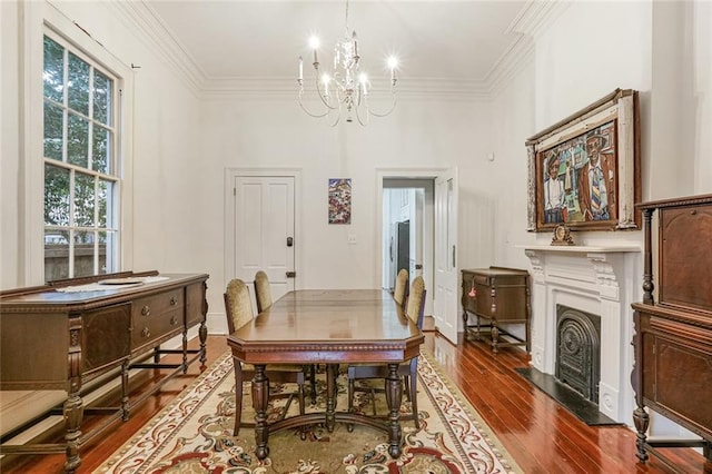 dining space featuring wood-type flooring, ornamental molding, and a chandelier