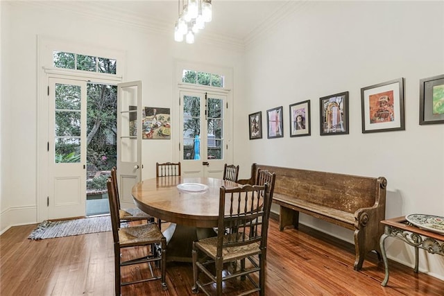 dining area with crown molding, a wealth of natural light, a chandelier, and wood-type flooring