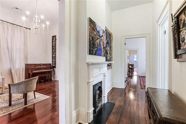 hallway with ornamental molding, dark hardwood / wood-style floors, and a notable chandelier