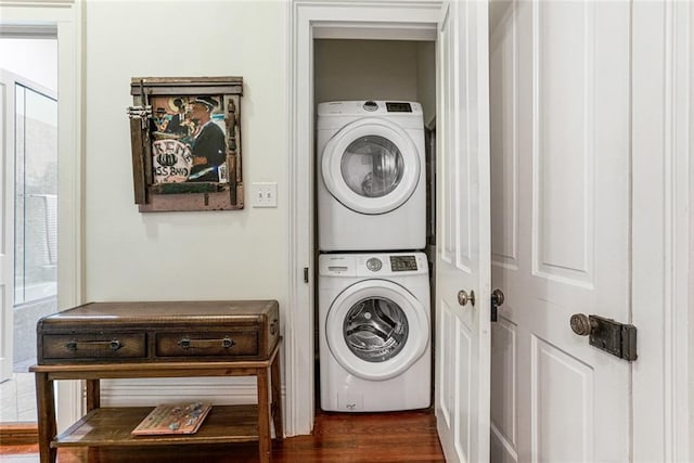 laundry area featuring stacked washer / drying machine and dark hardwood / wood-style flooring