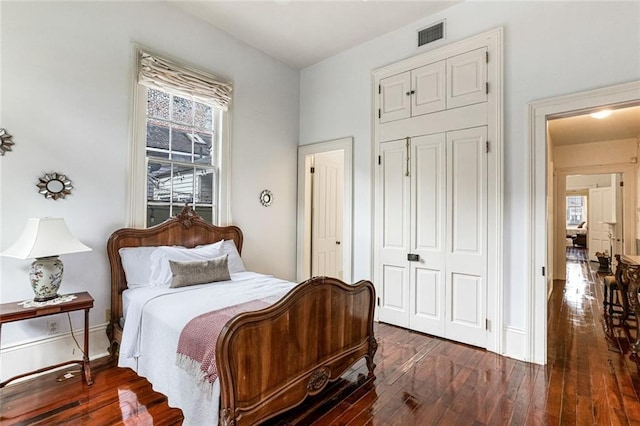 bedroom with dark hardwood / wood-style flooring and a closet