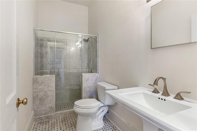 bathroom featuring sink, a shower with door, and toilet