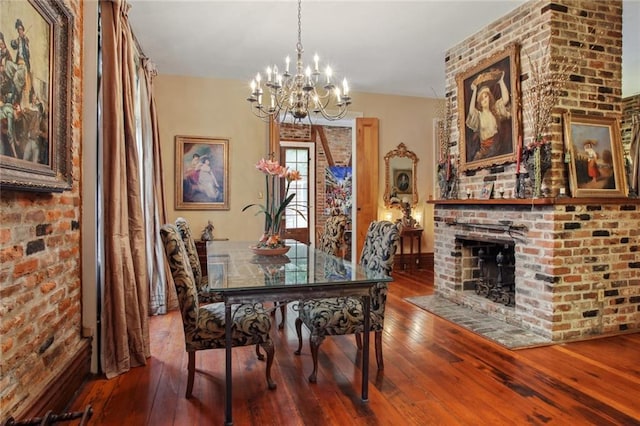 dining area featuring a brick fireplace, a chandelier, and wood-type flooring