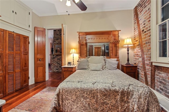 bedroom with ceiling fan, dark wood-type flooring, ornamental molding, and a closet