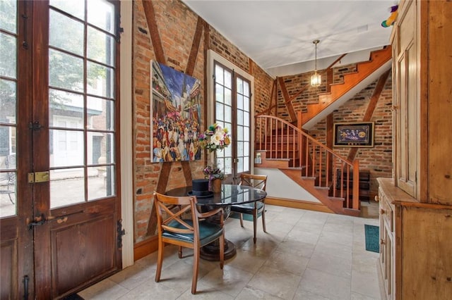 dining space featuring brick wall and french doors