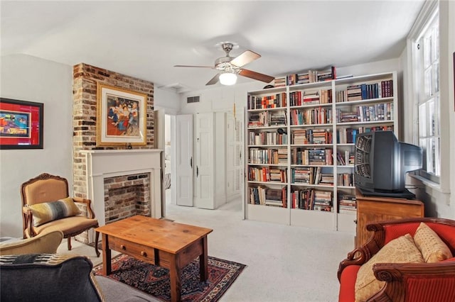 sitting room featuring a brick fireplace, light carpet, and ceiling fan