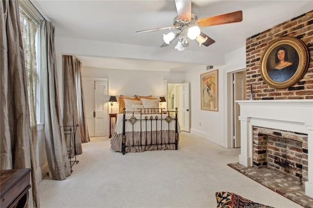 carpeted bedroom featuring ceiling fan and a fireplace