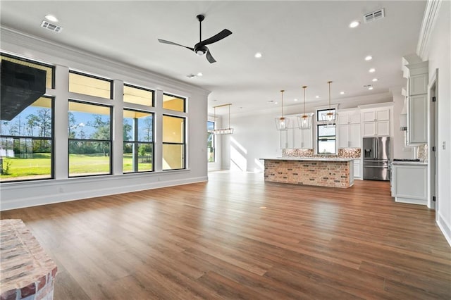 unfurnished living room featuring ceiling fan, ornamental molding, and dark wood-type flooring