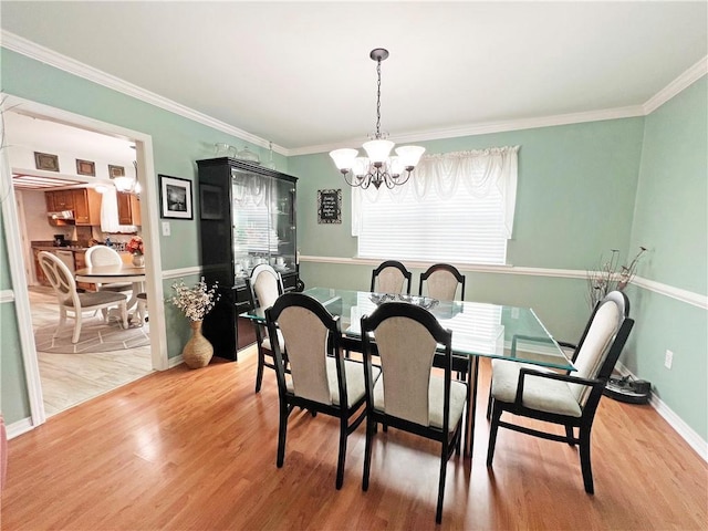 dining room with an inviting chandelier, light hardwood / wood-style floors, and crown molding